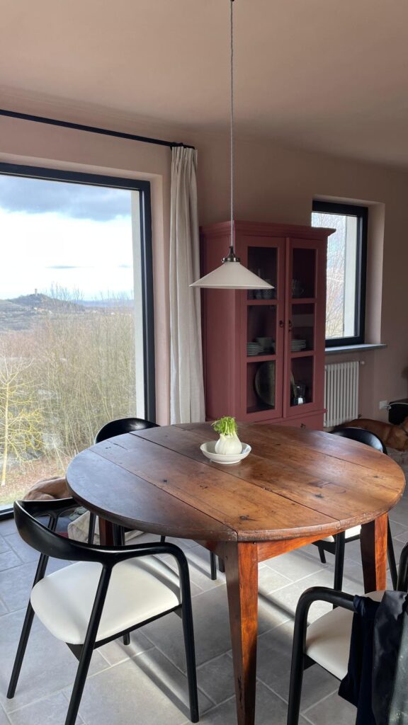 Faciliteiten. De eettafel met uitzicht door een groot raam. Gezellige franse lamp boven de oude ronde tafel.