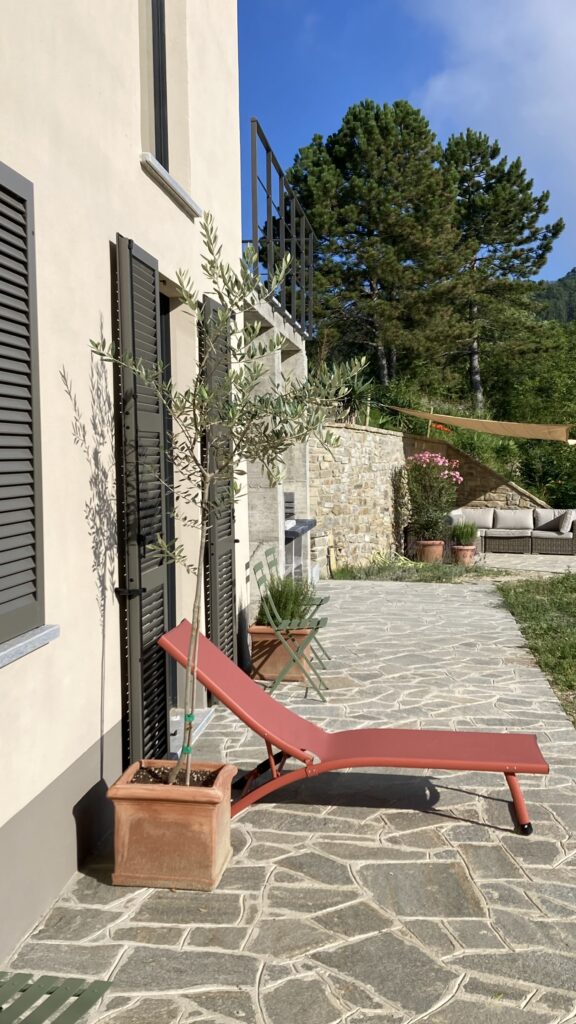 Het beneden terras, hier kan je heerlijk in de zon of schaduw zitten. Achterin zie het terras met de loungebank.